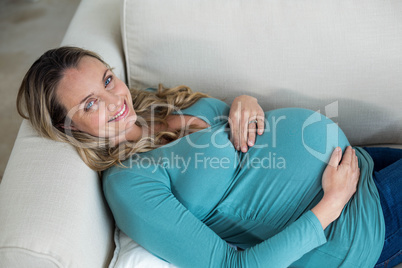 Pregnant woman touching her belly lying on the couch