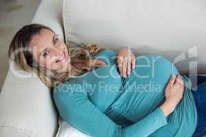 Pregnant woman touching her belly lying on the couch