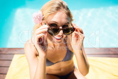 Smiling blonde in bikini sitting on towel