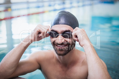 Smiling man wearing swim cap and goggles