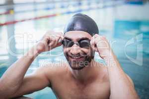 Smiling man wearing swim cap and goggles