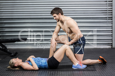 Male trainer assisting woman with sit ups