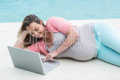 Pregnant woman relaxing outside using laptop