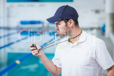 Handsome trainer blowing whistle and looking at stopwatch