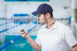 Handsome trainer blowing whistle and looking at stopwatch