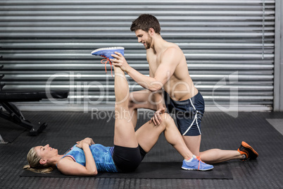 Male trainer assisting woman stretching