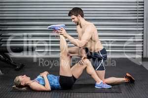 Male trainer assisting woman stretching