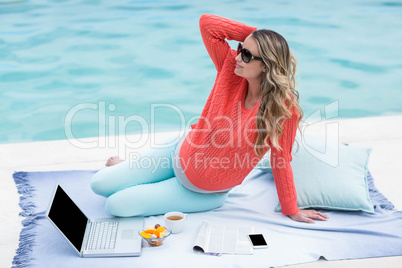 Pregnant woman relaxing outside and using laptop