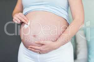 Pregnant woman applying cream on her belly