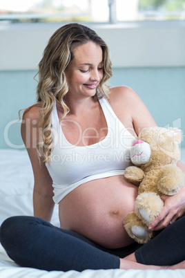 Pregnant woman sitting with a teddy bear