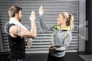 Fit couple high fiving in crossfit gym