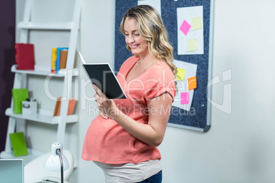 Pregnant woman reading a notebook