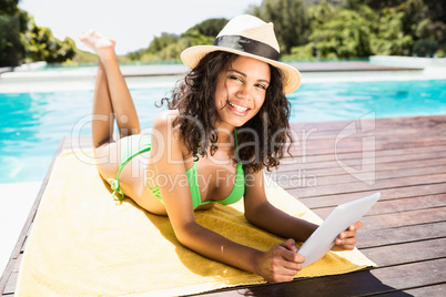 Fit brunette lying on towel and using tablet