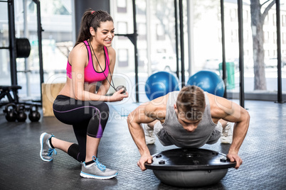 Athletic man working out helped by trainer woman