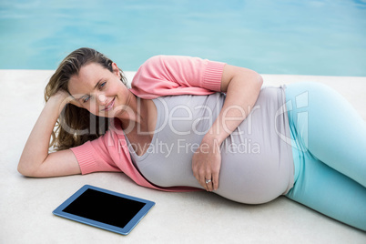 Pregnant woman relaxing outside using tablet