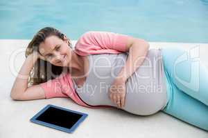 Pregnant woman relaxing outside using tablet