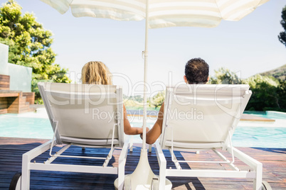 Rear view of couple on deck chairs