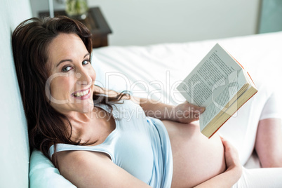 Pregnant woman on bed reading a book