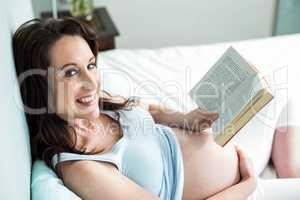 Pregnant woman on bed reading a book