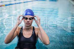 Fit woman wearing swim cap and goggles in the water