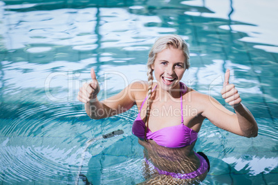 Fit woman doing underwater bike with thumbs up