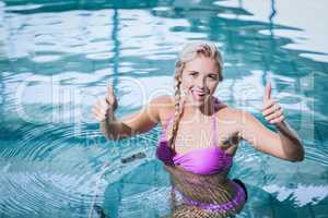 Fit woman doing underwater bike with thumbs up