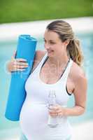 Pregnant woman holding water bottle and mat