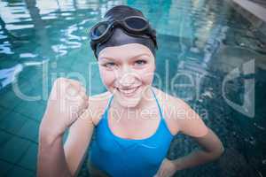 Fit woman wearing swim cap and goggles with raised fist