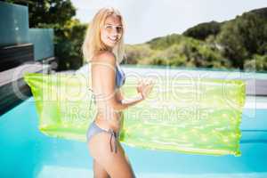 Beautiful blonde in bikini holding lilo
