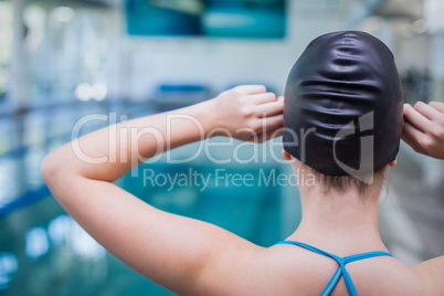 Rear view of fit woman putting on swim cap