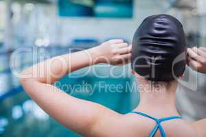 Rear view of fit woman putting on swim cap