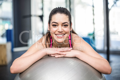 Smiling fit woman leaning on fitness ball