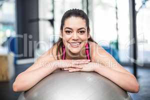 Smiling fit woman leaning on fitness ball
