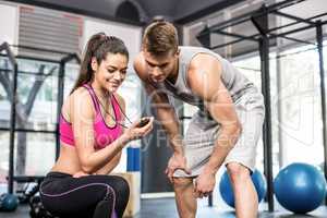 Athletic man checking time with trainer woman
