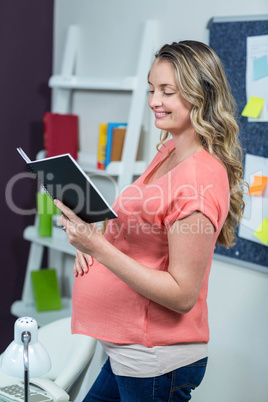 Pregnant woman reading a notebook