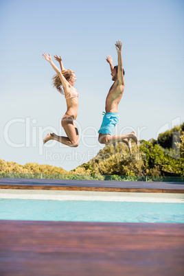 Happy couple jumping in the pool