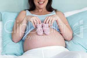 Pregnant woman with knitted slippers on her belly