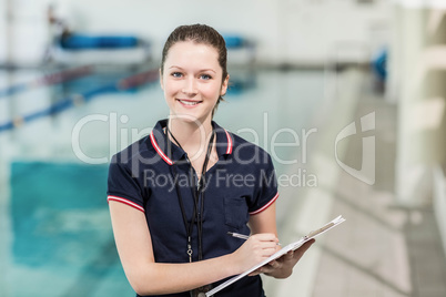 Pretty trainer writing on clipboard