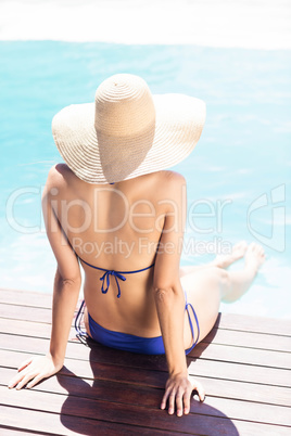 Woman with hat sitting on pools edge
