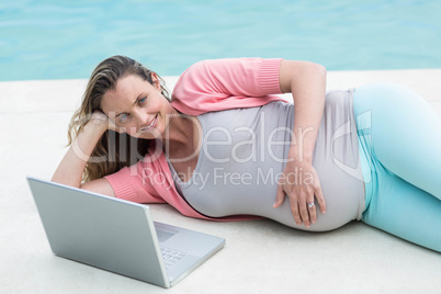 Pregnant woman relaxing outside using laptop