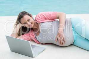 Pregnant woman relaxing outside using laptop