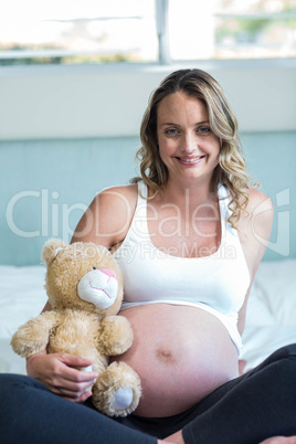 Pregnant woman sitting with a teddy bear