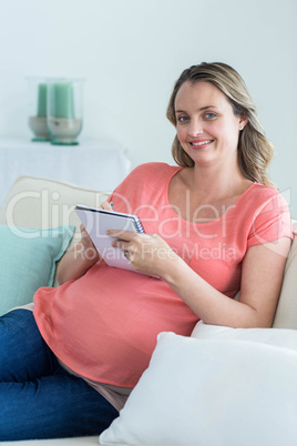 Pregnant woman writing on notepad