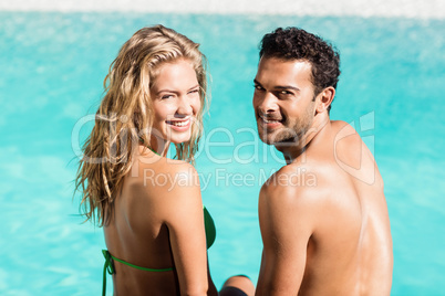 Rear view of couple sitting by the pool