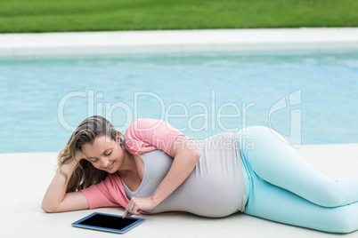 Pregnant woman relaxing outside using tablet