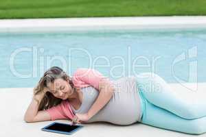 Pregnant woman relaxing outside using tablet