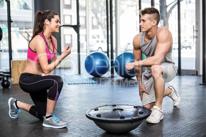 Athletic man working out helped by trainer woman