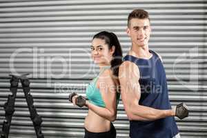 Fit people lifting dumbbells back to back