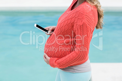 Pregnant woman touching her belly and texting