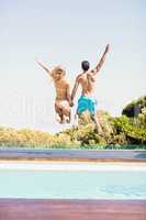 Happy couple jumping in the pool